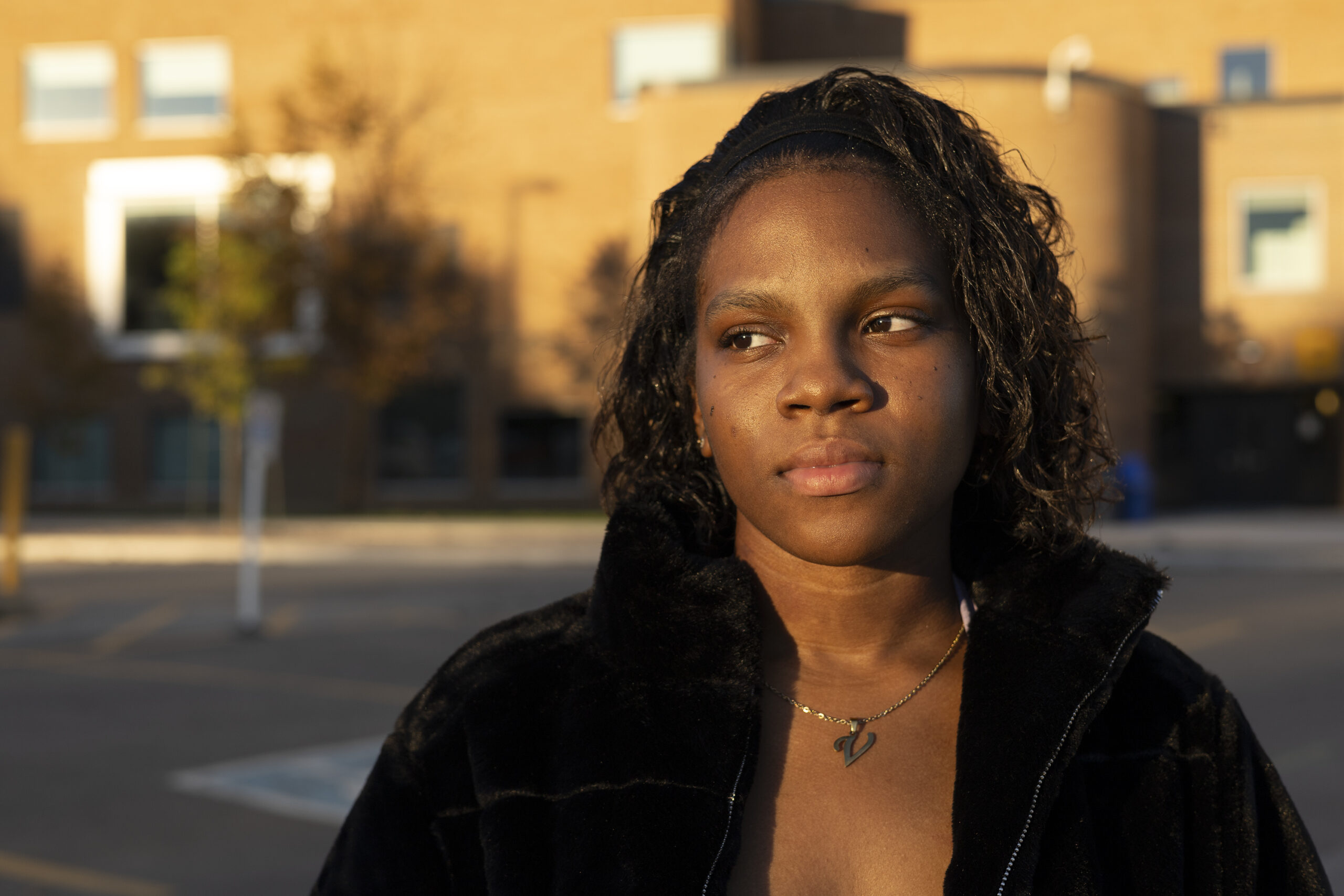 Woman in a black coat looking to her right as the sun sets.